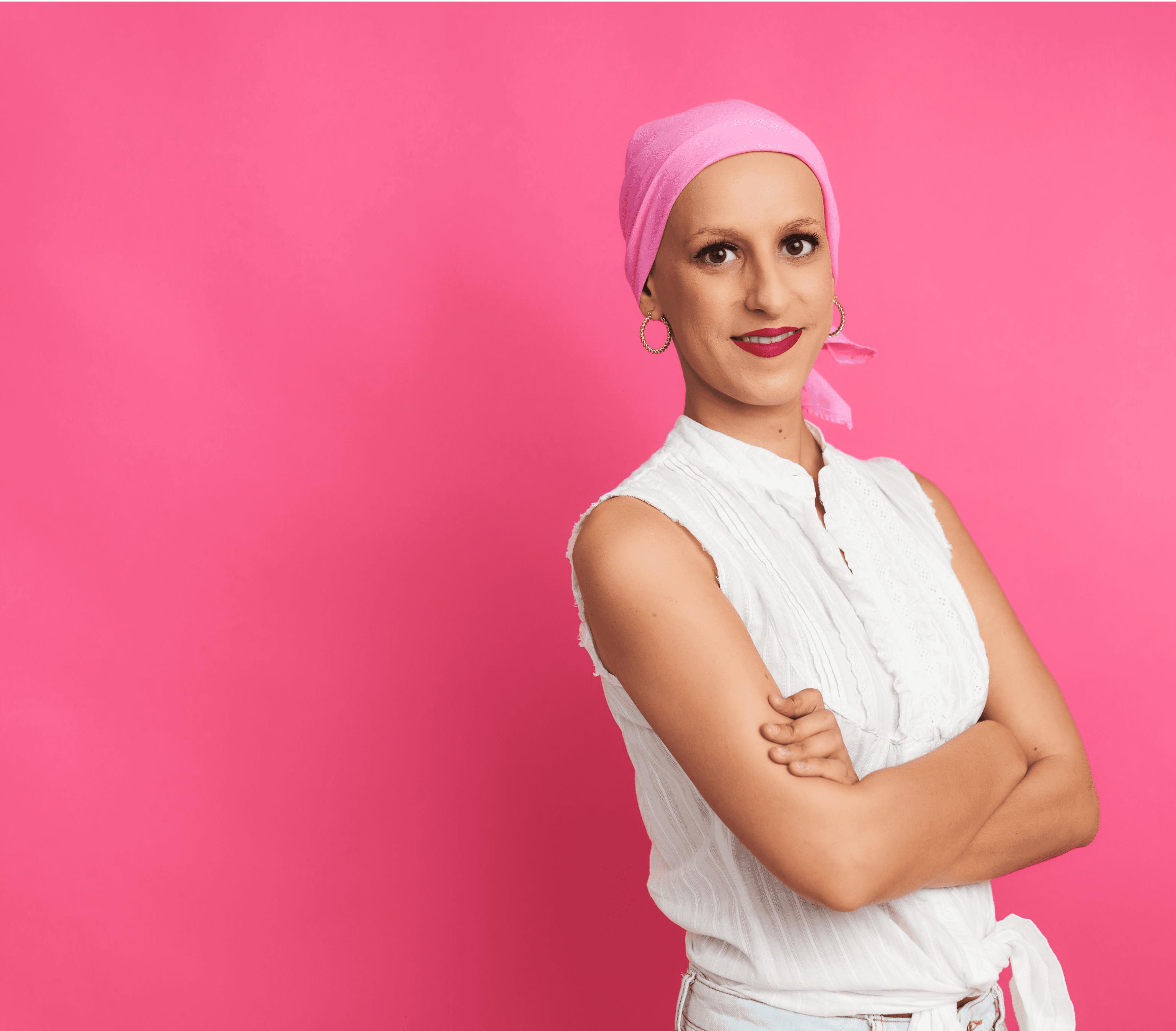 Woman wearing a pink headscarf, arms folded, smiling